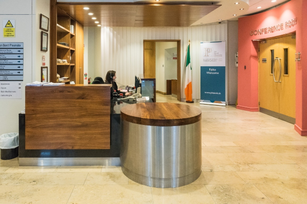 Entrance in front of porch doors: facing straight ahead (twelve o'clock position). On entering the building and stood in front of the porch doors this is what is in front of you at twelve o'clock position. In this the reception desk and assistance is immediately ahead at twelve o'clock position. The entrance to the Maoilbhríde Conference Room, is at 2 o'clock position.